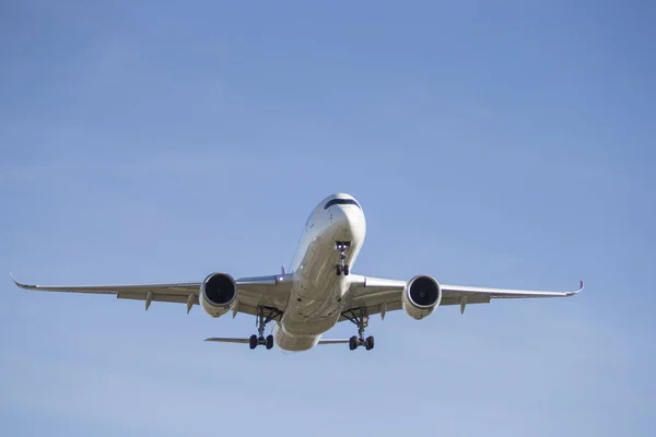 White commercial aircraft, seen from the front with the landing gear open. Transport concept.