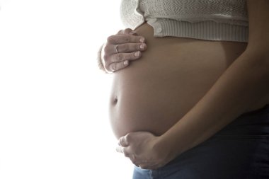 Hamile anne elleriyle karnını okşuyor..