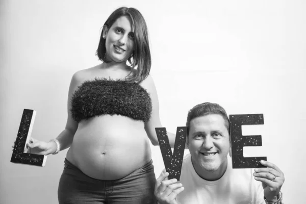 Pregnant couple smiling with the letters love. Black and white photo.