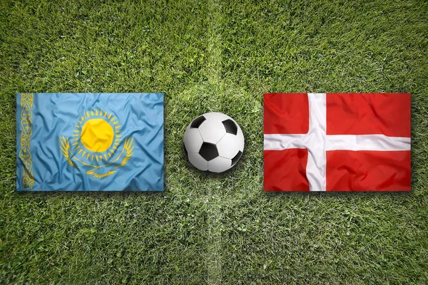 Прапори Казахстан проти Данії на футбольному полі — стокове фото