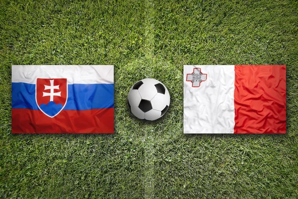 Slovakien vs Malta flaggor på fotbollsplan — Stockfoto