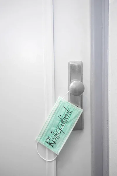 带有文字风险病人的公寓楼门上的绿色医疗面具 — 图库照片