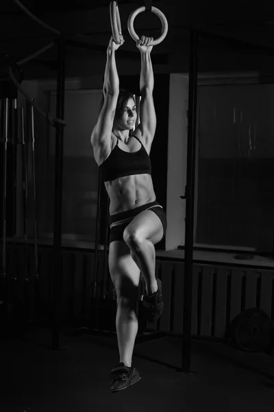Подходящая молодая женщина на гимнастских кольцах — стоковое фото