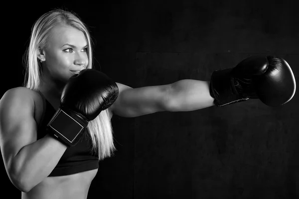 Menina com luvas de boxe em um fundo preto — Fotografia de Stock