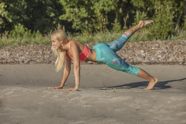 Młoda kobieta robi push up na plaży — Zdjęcie stockowe