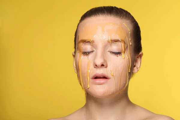 Vacker kvinna med honung på hennes ansikte — Stockfoto