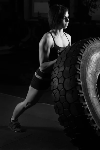 Ajuste atleta femenina realizando una voltereta de neumático — Foto de Stock