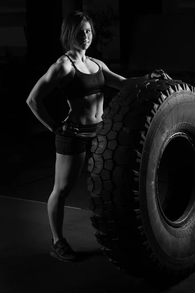 Fit female athlete performing a tire flip — Stock Photo, Image