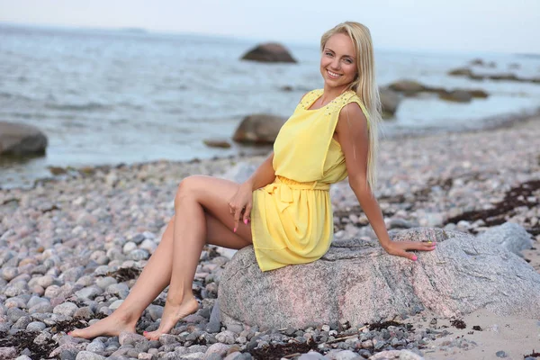 Blonde girl in a yellow dress on the beach — Stock Photo, Image