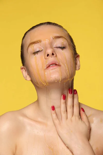 Vacker kvinna med honung på hennes ansikte — Stockfoto
