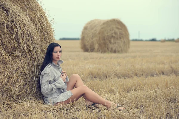 Woman sitting in field with haystacks — Stock Photo, Image