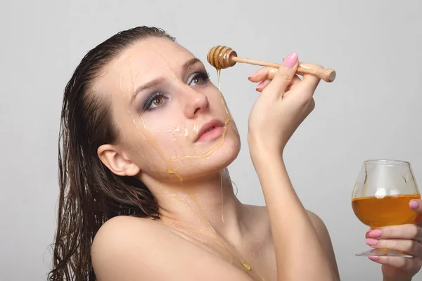 Hermosa mujer con miel en la cara — Foto de Stock