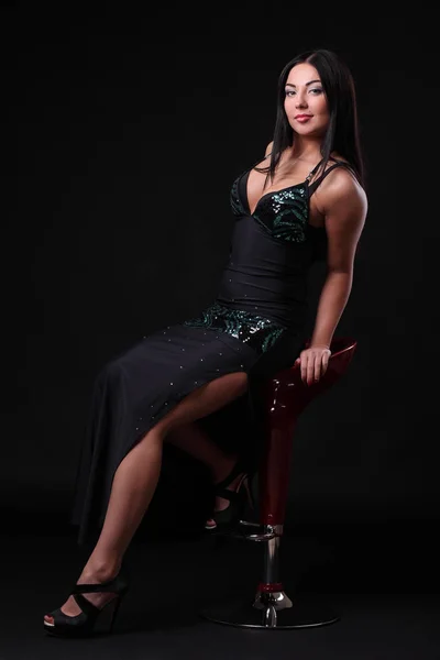 Молода дівчина в чорній сукні на барній стільці — стокове фото
