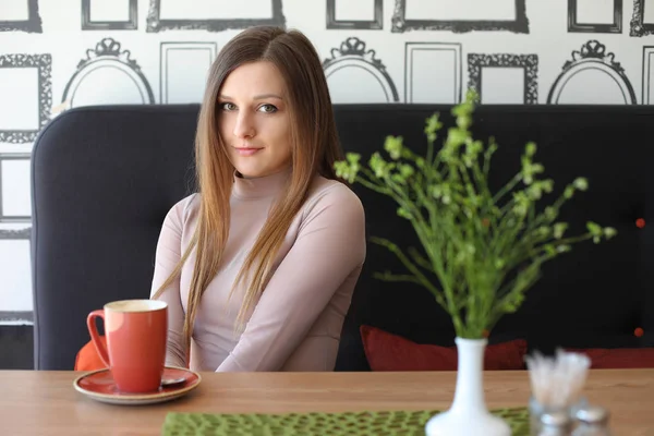 Girl in a cafeteria with a mug of tea or coffee — Stock Photo, Image