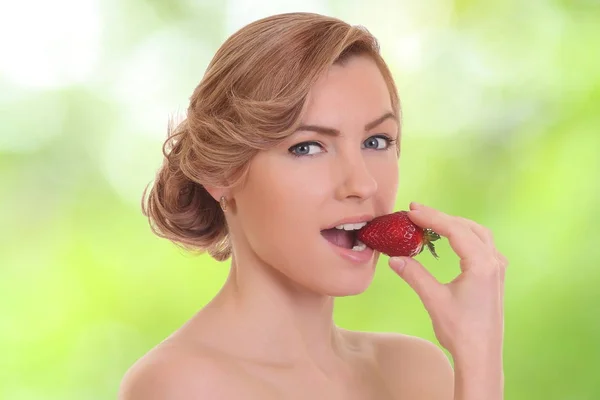 Young woman is eating red berry — Stock Photo, Image