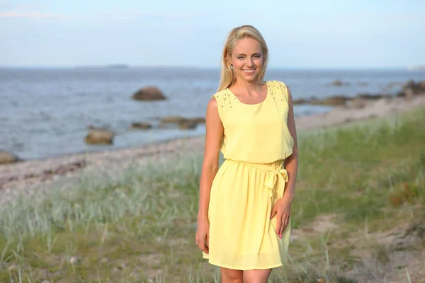 Блондинка в жёлтом платье на пляже — стоковое фото
