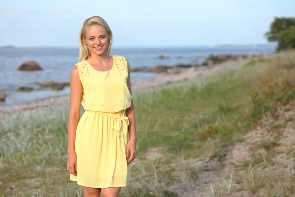 Menina loira em um vestido amarelo na praia — Fotografia de Stock