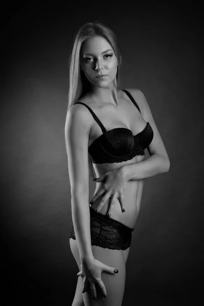 Jonge sexy meisje in ondergoed op een zwarte achtergrond — Stockfoto