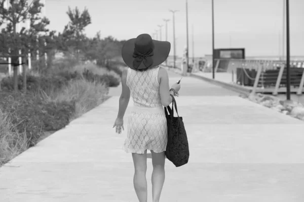 Mulher com saco e cabeça caminha rua abaixo — Fotografia de Stock
