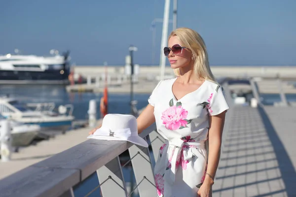 Молода жінка з капелюхом стоїть біля човнів у яхті — стокове фото