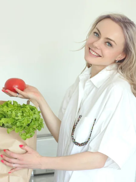 Молодая позитивная улыбающаяся женщина с овощами на кухне — стоковое фото