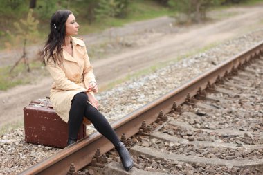 Raylarda bavullu bir kadın.