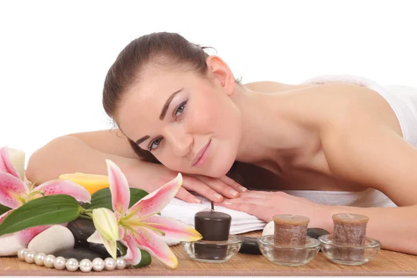 Jonge vrouw op massagetafel met kaarsen — Stockfoto