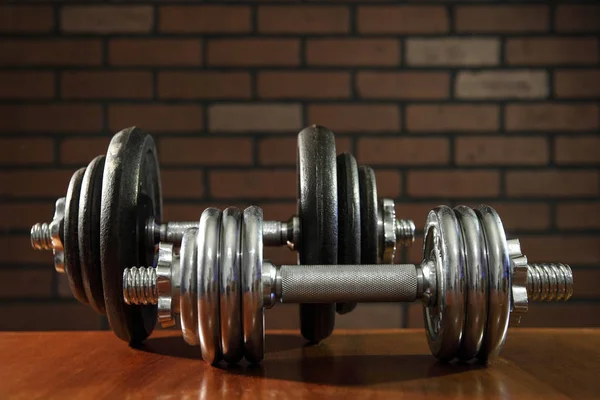 Iron dumbbells on brick wall background — Stok fotoğraf