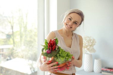 Mutfakta sebzeli güzel, pozitif gülümseyen bir kadın.