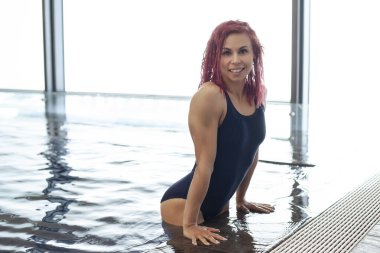 Havuzda mavi mayolu, gülümseyen atletik kız.