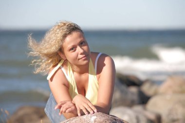 Genç güzel yetişkin kız deniz kenarında poz veriyor.