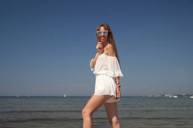 Deniz kenarındaki beyaz elbiseli mutlu genç kız