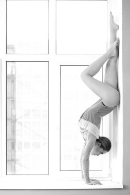 Mayo giymiş atletik kadın pencerede poz veriyor.