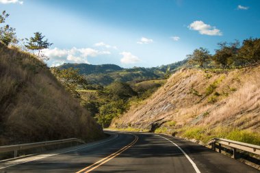 Dağlı, mavi gökyüzü ve bulutlu bir yol