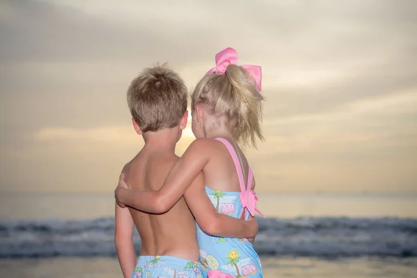 Siblings hugging at the beach.