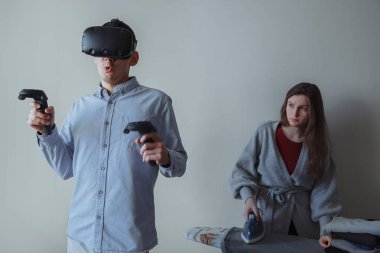 Koca sanal gerçeklik gözlükleriyle eğleniyor. Karım ev işi yapıyor..