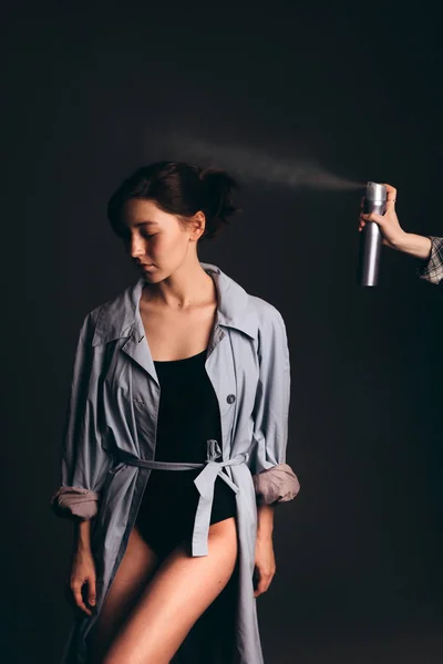 Kızlar saçlarına saç spreyi sıkar. Kız siyah mayo ve mavi pelerin giyiyor..