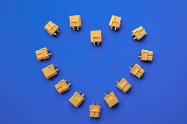 Heart made of yellow XT-60 connectors for power supply on a blue background. The heart of an electronic engineer.