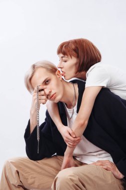 Red-haired girl hugs a man. The blond looks in the frame and closes 1 eye. People are depicted on a white background.