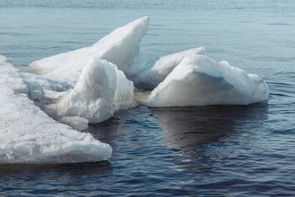 A derreter gelo no Volga. O gelo branco nevado cai na água azul. O gelo foi batido em uma pilha pela corrente . — Fotografia de Stock