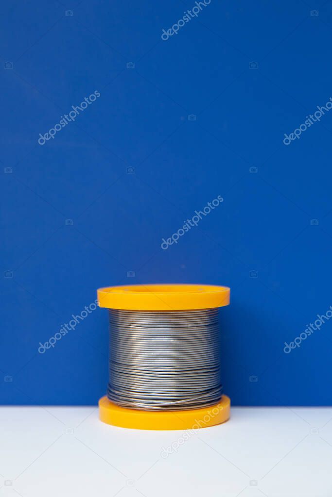A yellow coil of solder stands in the frame. The coil stands on the white and blue media section. 