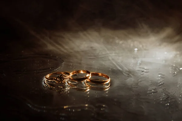 Karakter dari keluarga. Tiga cincin emas berbaring berdampingan. 2 cincin kawin dan 1 cincin pertunangan. — Stok Foto