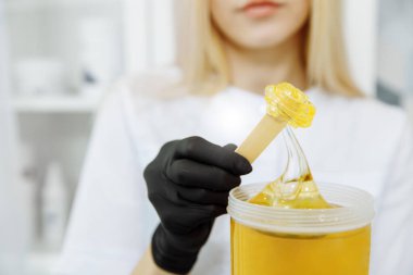 Cesedi yaza hazırlıyorum. Kız spatulaya balmumu sürüyor. Balmumu şeffaf ve altın rengi var.. 