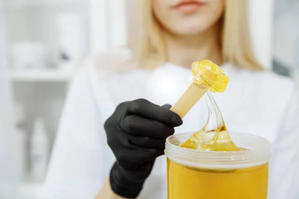 Cesedi yaza hazırlıyorum. Kız spatulaya balmumu sürüyor. Balmumu şeffaf ve altın rengi var.. 