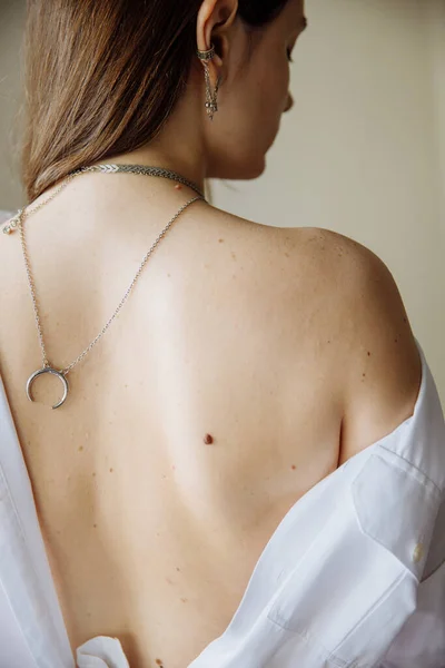 Female back with moles and freckles with natural light. Her dark hair was draped over her shoulders.