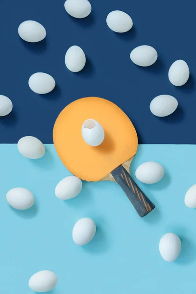 Sarı raket masanın tam ortasındadır. Raketin üzerinde kırık bir yumurta var. Etrafta başka yumurtalar da var.. — Stok fotoğraf