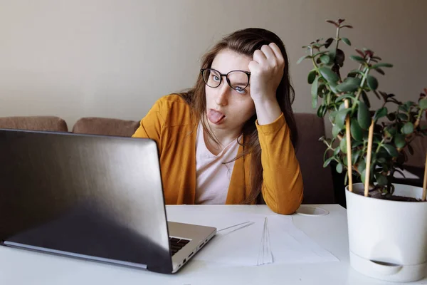 Difficulties of virtual communication from the home office. The girl is Sitting in front of a laptop.