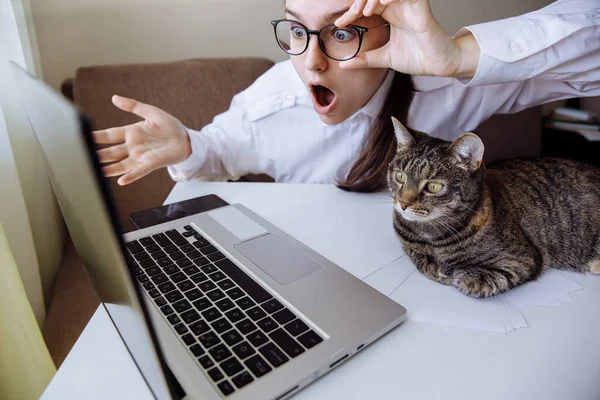 The girl and the cat look at the monitor in surprise. The girl adjusts her glasses. The mans mouth is open in surprise.
