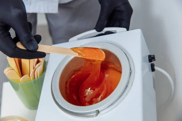 Ağda yapmayı. Kadınlar tuvaleti. Sekizinci adımın dördüncüsü. Balmumunun ısınmasını bekle ve bir spatulayla temizle..