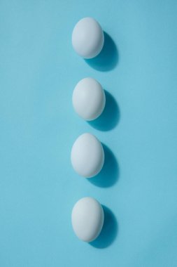 Dört beyaz yumurta tam olarak bir sırada yatar. Bir gölge bırakıyorlar. Yumurtaların keskin kenarı farklı yönlere yönelir..